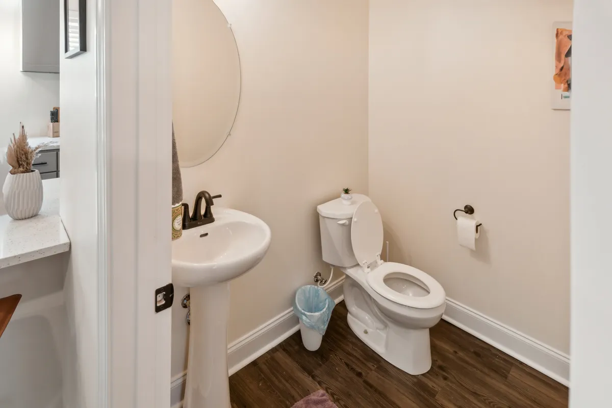 This image depicts a compact and modern powder room featuring a sink, toilet, and a clean mirror. The overall design is minimalist, with crisp lines and uncluttered surfaces, supporting a mood of functional ease and quick access for guests needing a convenient freshen-up.