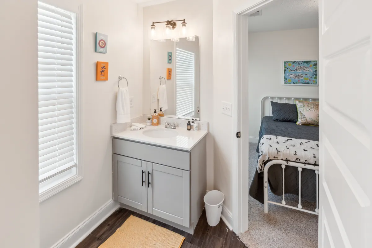 A cheerful powder room with a vanity sink, mirror, colorful wall art, and towel rack, offering a bright and functional space for quick refreshes and daily routines.